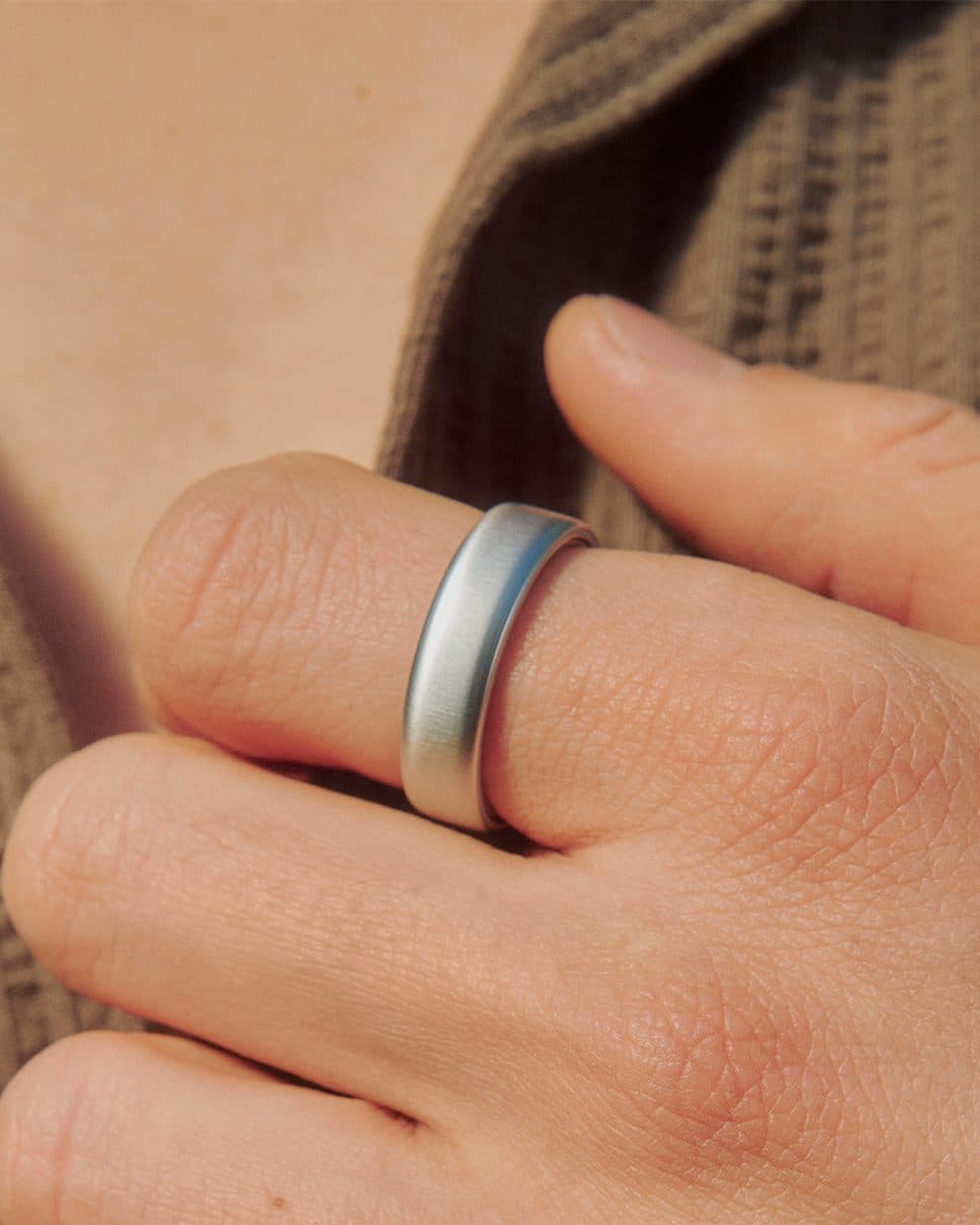 Eine Hand mit dem Oura Ring 5 in gebürstetem Silber